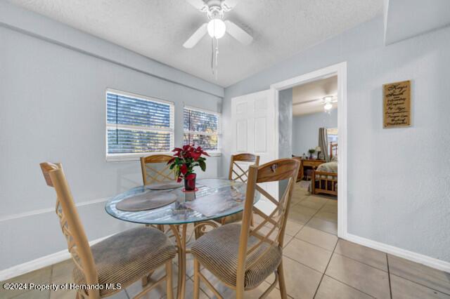 tiled dining area featuring a textured ceiling and ceiling fan