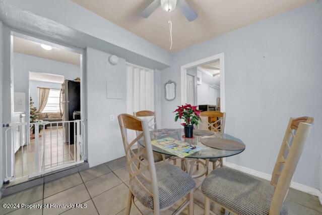 dining space with ceiling fan and light tile patterned flooring