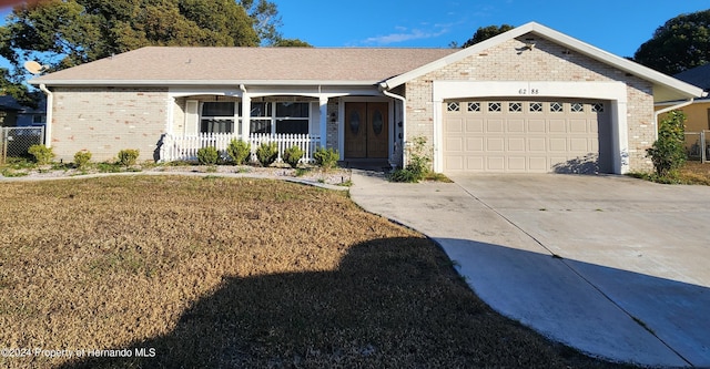 ranch-style home with a front lawn, a porch, and a garage