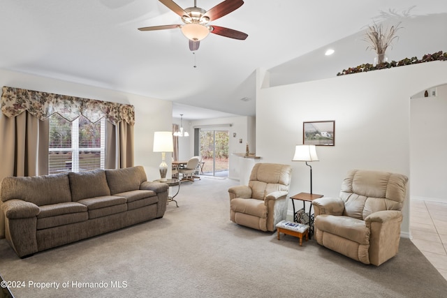 tiled living room with ceiling fan with notable chandelier and vaulted ceiling