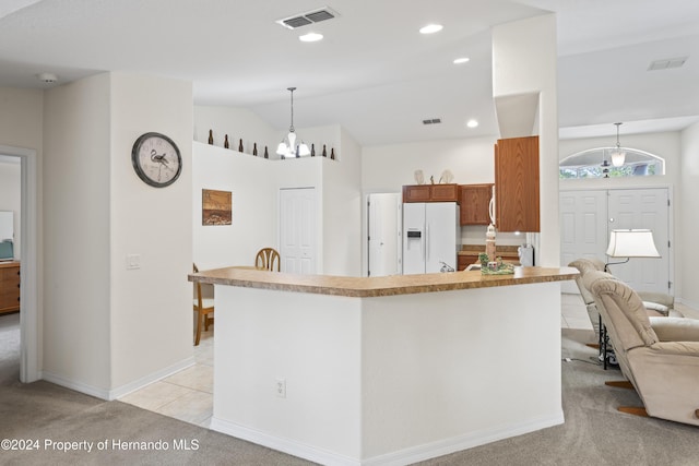 kitchen with pendant lighting, lofted ceiling, white refrigerator with ice dispenser, light carpet, and an inviting chandelier