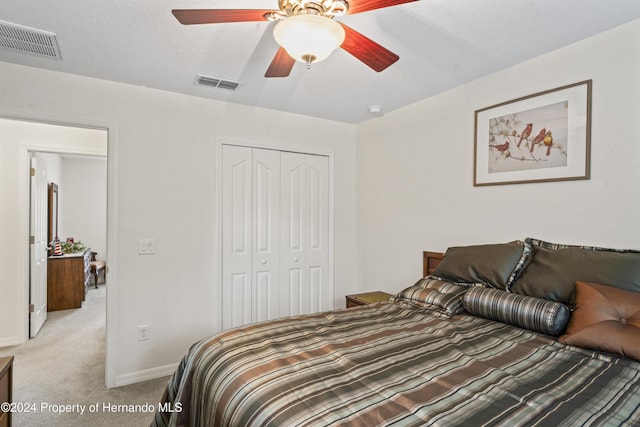 carpeted bedroom with ceiling fan, a closet, and a textured ceiling