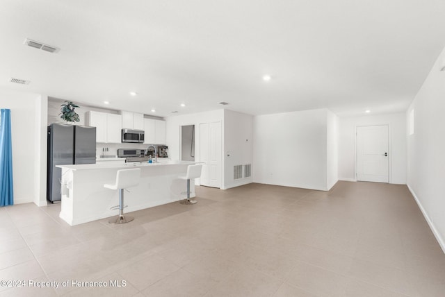 kitchen with a center island with sink, a kitchen breakfast bar, sink, white cabinetry, and stainless steel appliances