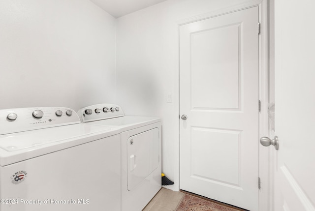 clothes washing area featuring washer and clothes dryer and light tile patterned floors