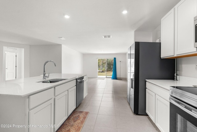 kitchen featuring appliances with stainless steel finishes, sink, light tile patterned floors, white cabinetry, and an island with sink