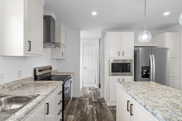 kitchen featuring dark wood-type flooring, wall chimney range hood, decorative light fixtures, white cabinetry, and stainless steel appliances