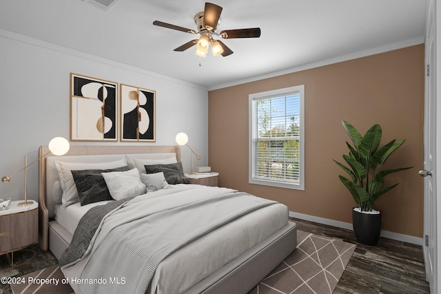 bedroom with dark hardwood / wood-style floors, ceiling fan, and ornamental molding