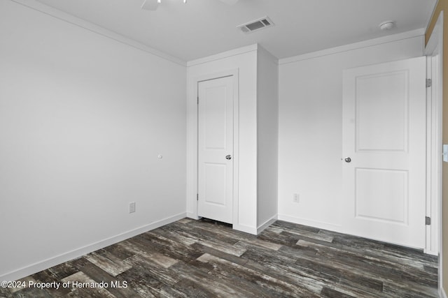 unfurnished bedroom with dark hardwood / wood-style floors, ceiling fan, and crown molding