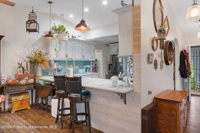 kitchen featuring hardwood / wood-style flooring, lofted ceiling, stainless steel refrigerator with ice dispenser, and tasteful backsplash