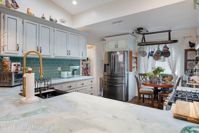 kitchen with decorative backsplash, sink, and stainless steel refrigerator with ice dispenser