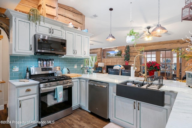 kitchen with dark wood-type flooring, white cabinetry, hanging light fixtures, and stainless steel appliances