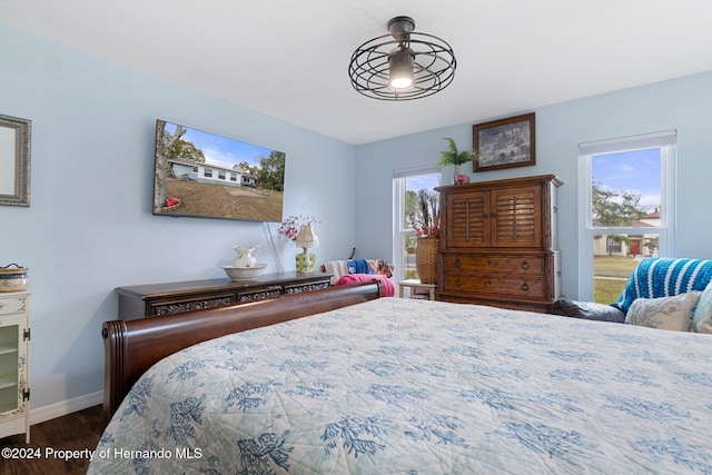 bedroom with multiple windows and dark wood-type flooring