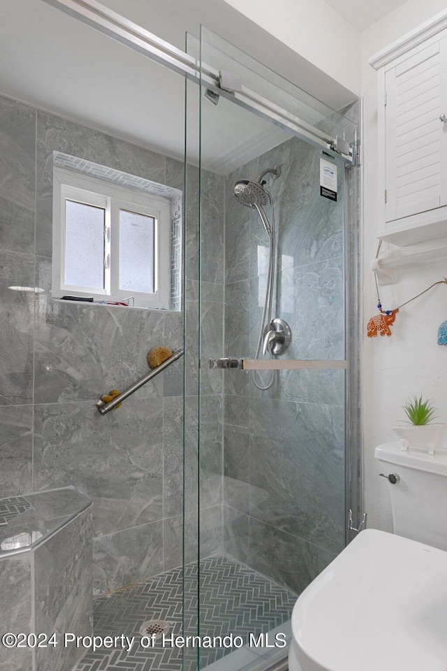 bathroom featuring a shower with door and toilet