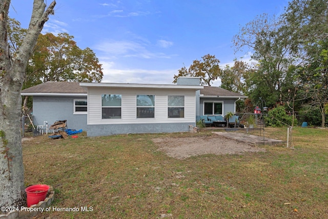 rear view of house featuring an outdoor living space and a yard