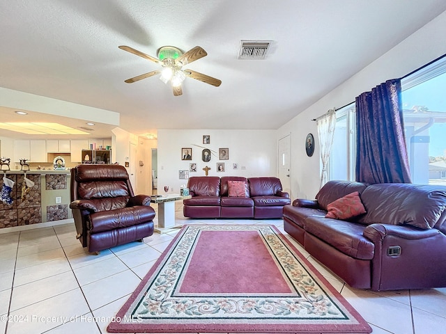 living room with a textured ceiling, ceiling fan, and light tile patterned flooring