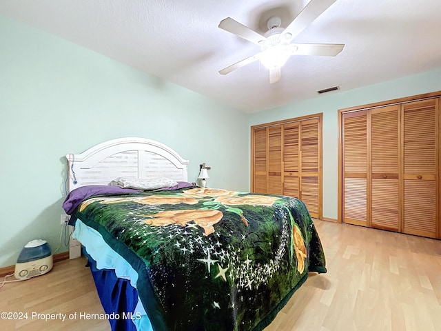 bedroom with multiple closets, ceiling fan, and wood-type flooring