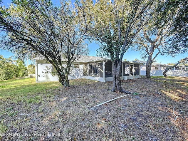 back of property featuring a lawn and a sunroom