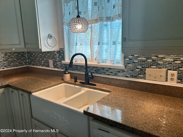 kitchen with sink, hanging light fixtures, tasteful backsplash, dark stone counters, and dishwashing machine