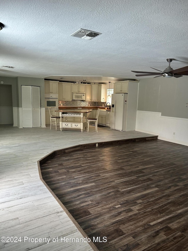 unfurnished dining area featuring wood-type flooring, a textured ceiling, and ceiling fan