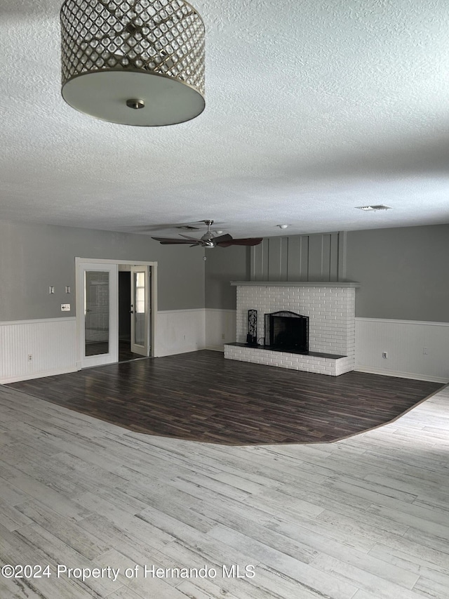 unfurnished living room featuring a fireplace, hardwood / wood-style floors, and a textured ceiling