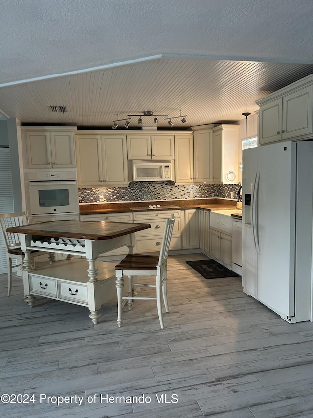 kitchen featuring pendant lighting, white appliances, light hardwood / wood-style floors, and tasteful backsplash