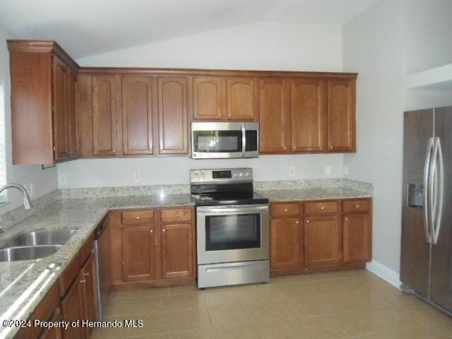 kitchen with sink, light tile patterned flooring, vaulted ceiling, and appliances with stainless steel finishes