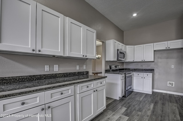 kitchen with dark stone counters, dark hardwood / wood-style floors, a textured ceiling, white cabinetry, and stainless steel appliances