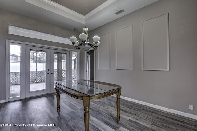 unfurnished dining area featuring dark wood-type flooring, an inviting chandelier, french doors, ornamental molding, and a tray ceiling