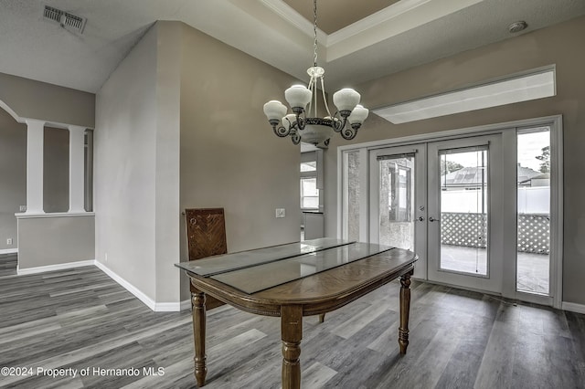 unfurnished dining area featuring hardwood / wood-style floors, a textured ceiling, an inviting chandelier, and french doors