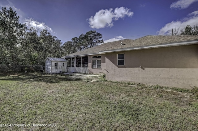 back of house with an outbuilding, stucco siding, a lawn, fence, and a shed