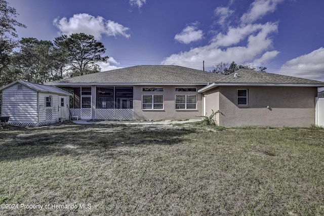 back of property featuring a sunroom, a storage shed, and a yard