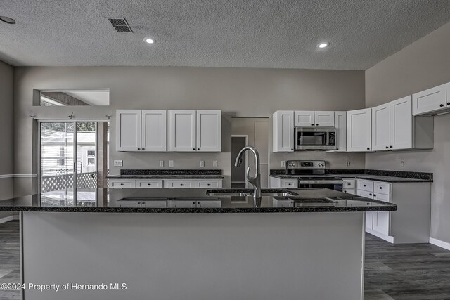 kitchen featuring a center island with sink, white cabinets, dark wood-type flooring, and appliances with stainless steel finishes