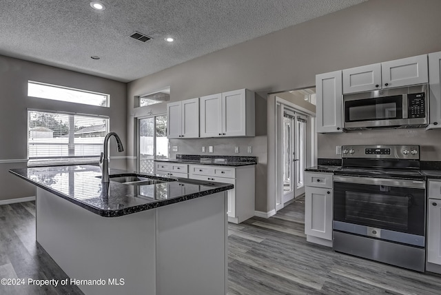 kitchen with visible vents, appliances with stainless steel finishes, wood finished floors, a textured ceiling, and a sink