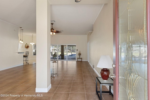 corridor featuring dark tile patterned flooring, a notable chandelier, and crown molding