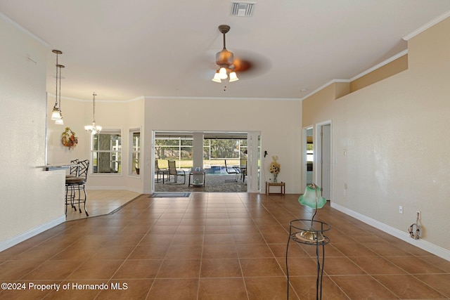 unfurnished living room with ceiling fan with notable chandelier, dark tile patterned floors, and crown molding