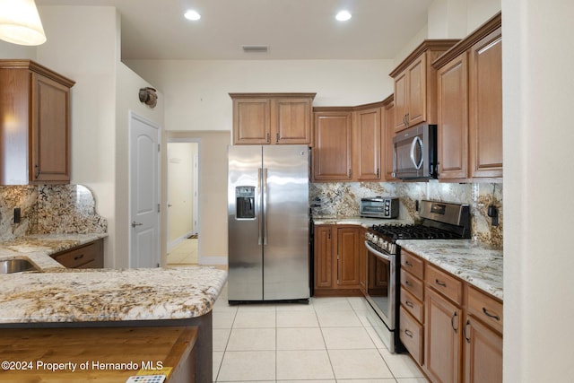 kitchen featuring backsplash, light stone counters, light tile patterned floors, and stainless steel appliances