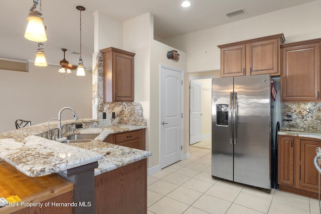 kitchen with a breakfast bar area, kitchen peninsula, stainless steel fridge, and sink