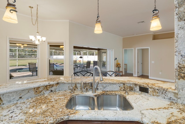 kitchen featuring light stone counters, hanging light fixtures, a notable chandelier, and sink