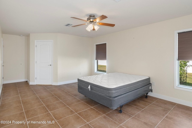 tiled bedroom featuring multiple windows and ceiling fan