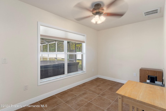 unfurnished office with dark tile patterned floors and ceiling fan