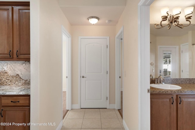 hall featuring light tile patterned flooring, sink, and a chandelier