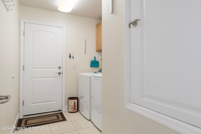 washroom featuring washer and dryer, light tile patterned floors, and cabinets