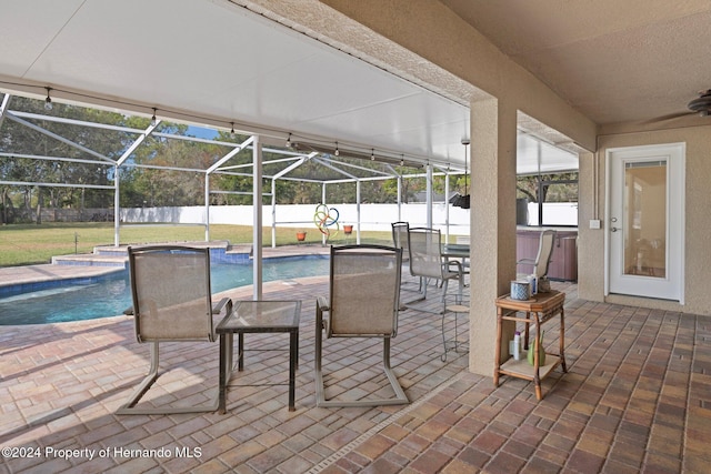 view of patio with a lanai, ceiling fan, and a pool with hot tub