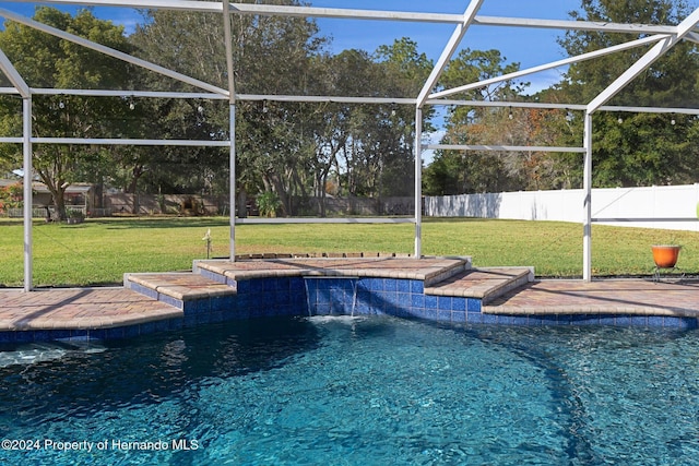 view of pool with pool water feature, a lanai, and a yard