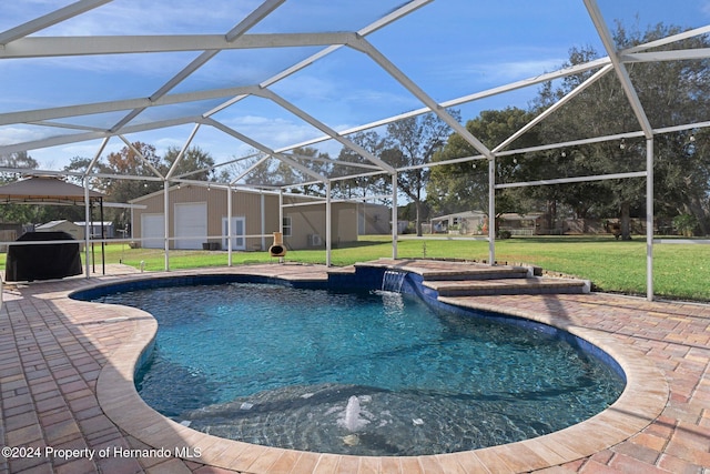 view of pool featuring pool water feature, glass enclosure, a patio area, and a yard