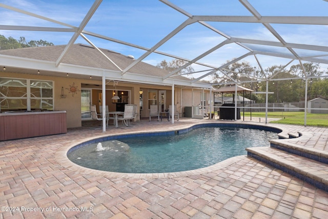 view of swimming pool with glass enclosure, ceiling fan, and a patio