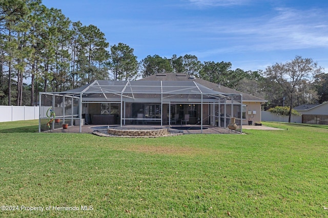 rear view of property featuring a lawn, glass enclosure, and a patio area