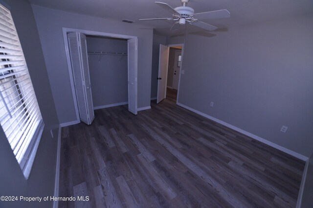 unfurnished bedroom with a closet, ceiling fan, and dark wood-type flooring