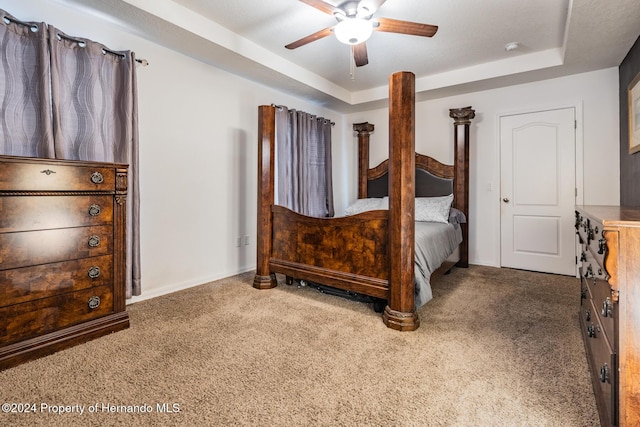 bedroom with a tray ceiling, ceiling fan, and carpet floors