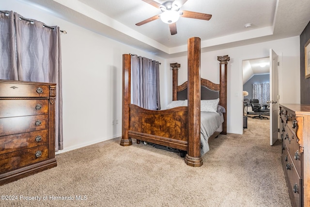 carpeted bedroom featuring a tray ceiling and ceiling fan